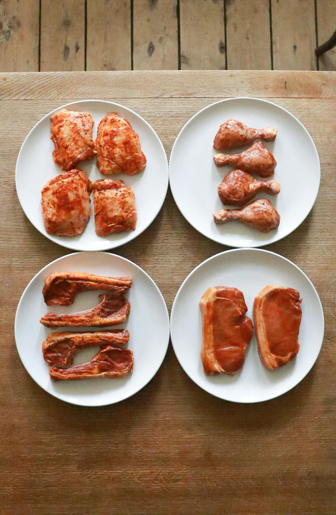 Plates of various fresh raw meat cuts with spices ready for a braai